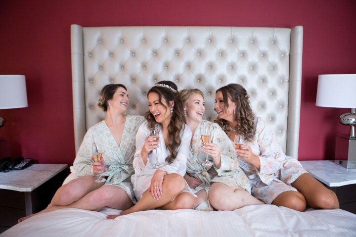 Bride and bridesmaids in matching robes sipping champagne