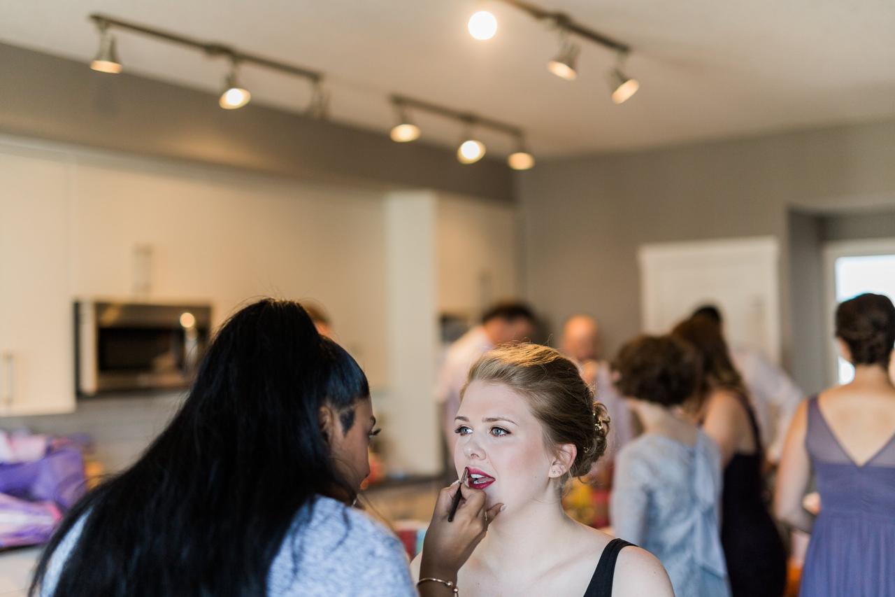 Bride getting lipstick applied by a makeup artist