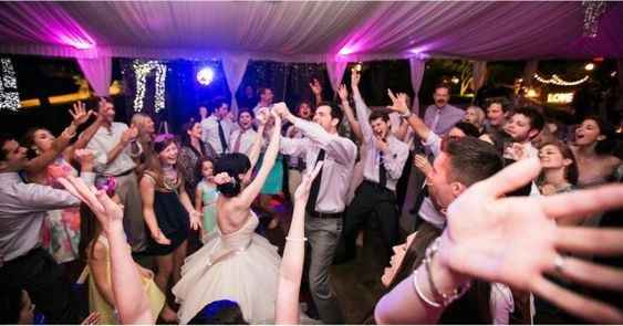 Everybody on the dance floor! Bride, groom, and guests party at reception
