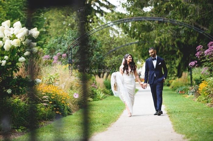 Bride and Groom Walking Hand in Hand Through Garden