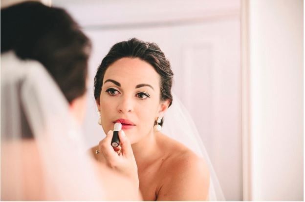 Bride Putting On Lipstick in Mirror