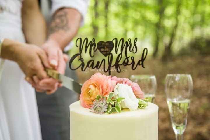 couple cutting a wedding cake, pink white and green flowers