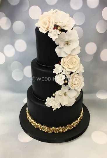black wedding cake with white roses cascading down the side