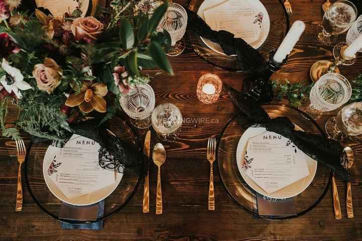 table setting with clear charger plates, gold cutlery, wild flowers and greener