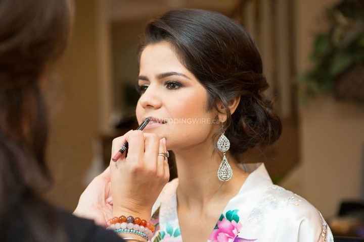 bride getting lipstick applied by makeup artist 