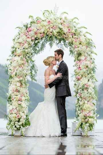 couple under flower arch, wedding ceremony