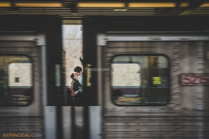 couple kissing in a train station, shot between train carts