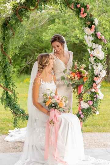 two brides in gowns with a floral backdrop