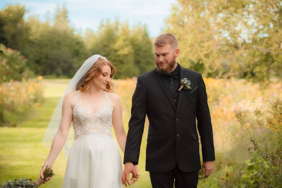 Bridal couple walk in meadow