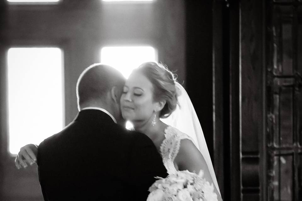 Backlit bride embraces father