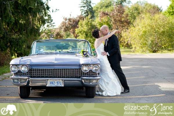 The bride and groom leaning on a vintage car with their noses touching.jpeg