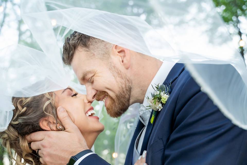 Newlyweds laughing under veil