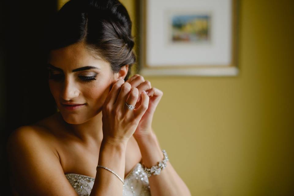 Bride putting on earrings