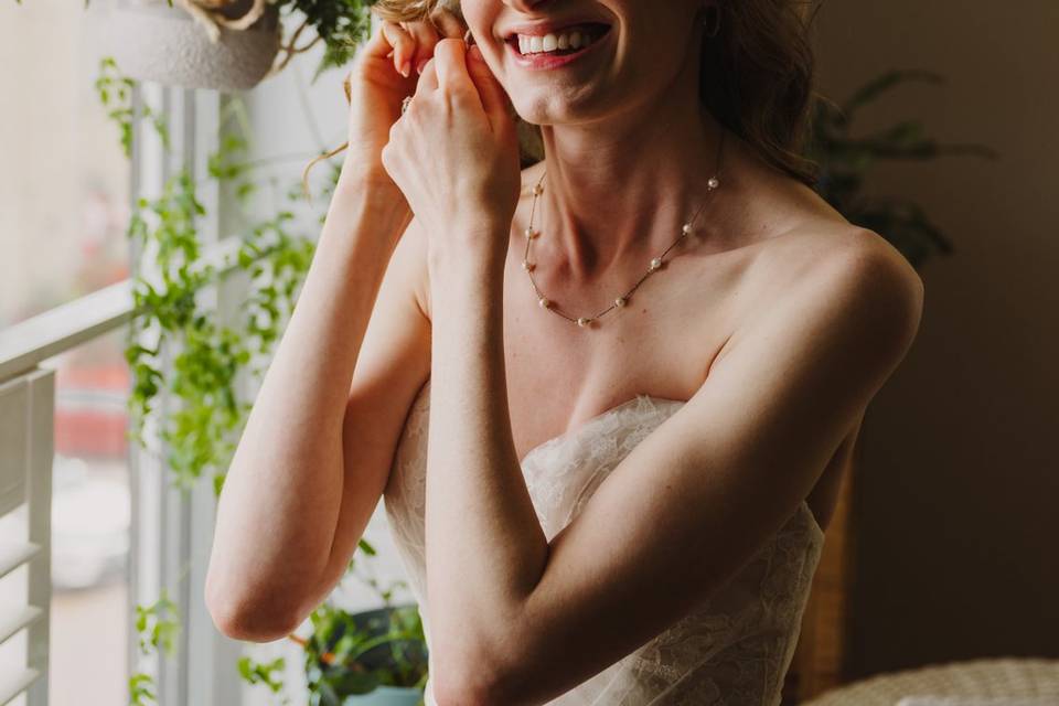 Bride putting on earrings